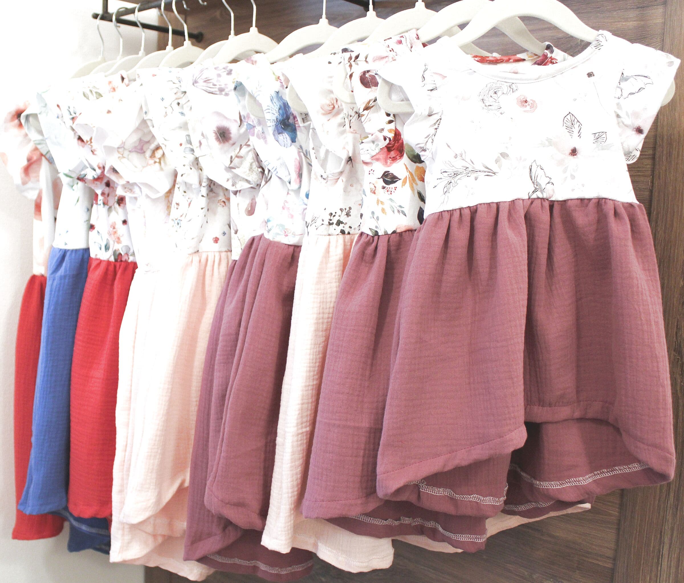 Handgenähte Kinderkleider mit Blumenstoffen und Musselinrock auf Bügeln